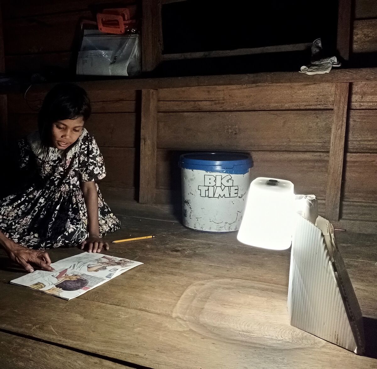 A girl doing homework beside a Light for Hope lantern