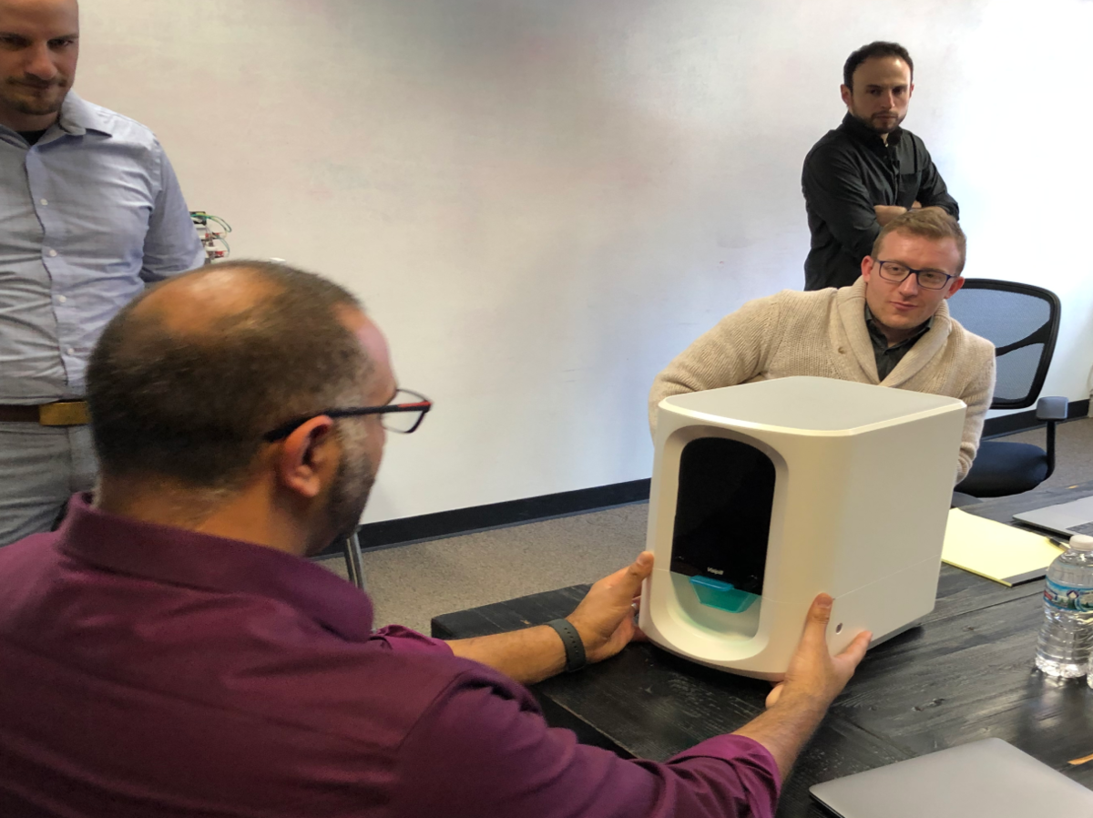 Engineers reviewing a VisiPill dispenser prototype at a table